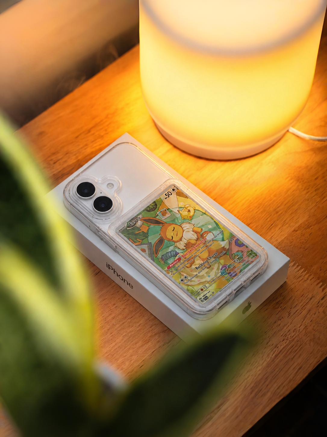 Phone case with colorful design on a wooden surface next to a lamp
